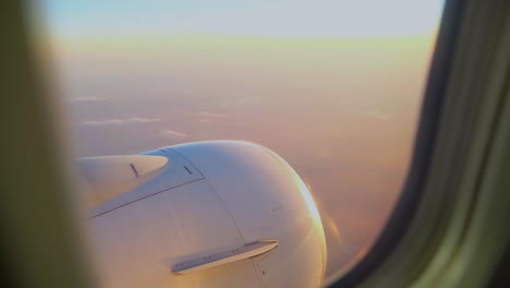 Vista-Escénica-Por-La-Ventana-De-Un-Avión-Con-Un-Cielo-De-Puesta-De-Sol-Rosa-Y-Vista-Del-Motor-De-Turbina