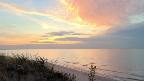 Ruhige-Wellen,-Die-Gegen-Einen-Leeren-Strand-Mit-Mystischem-Buntem-Himmel-Schlagen