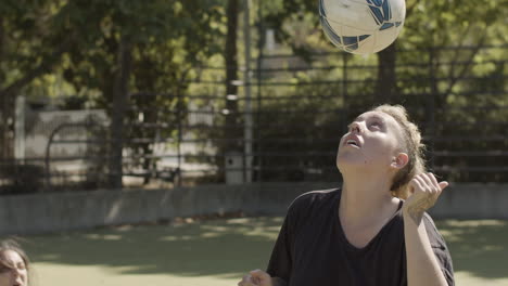 slow motion of focused female football player kicking soccer ball with head on the field