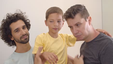 happy gay parents and son posing at home