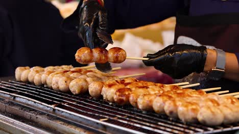 vendor grilling sausages at bangkok street food stall