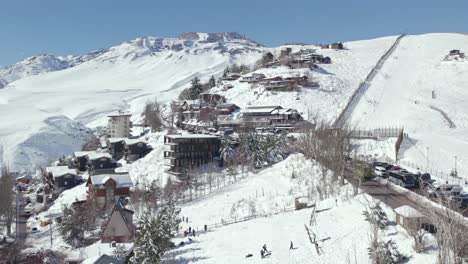 Vista-Aérea-De-Personas-Jugando-En-La-Ladera-De-Nieve-En-La-Estación-De-Nieve-De-Farellones,-Tiro-Ascendente