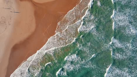 Hyperlapse-top-down-showing-waves-of-the-ocean-reaching-golden-beach-in-summer---France,-Europe