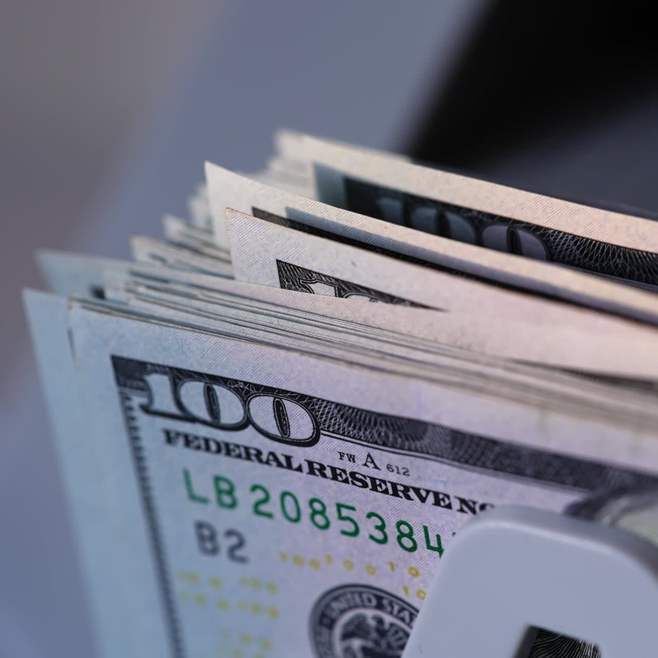 American currency hundred dollar bills falling on the holder of device. Close up. Money in cash counter machine