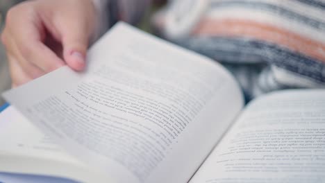 Close up of girl student turns page of a book while reading