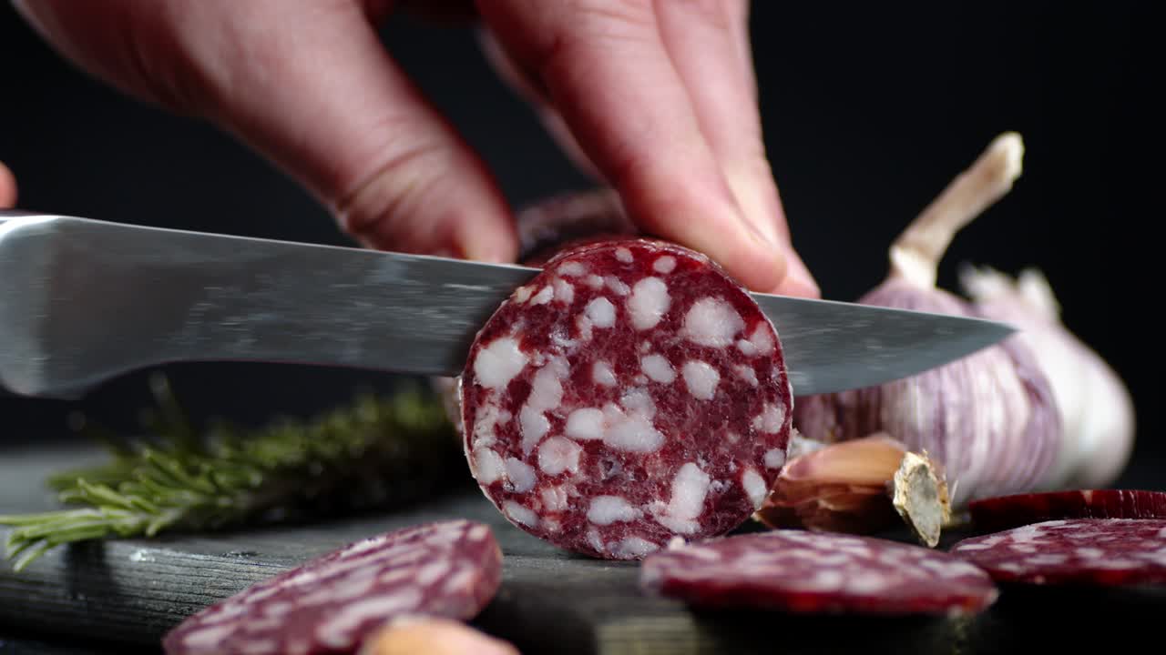 manos masculinas cortando salami en pedazos redondos.