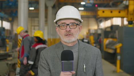 tv journalist in hardhat reporting on industrial plant