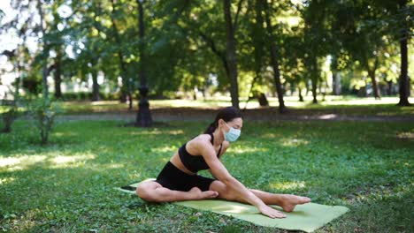 mujer practicando yoga en un parque con una máscara