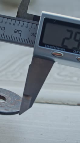 manos de ingeniero que utilizan una pinza de vernier para escalar la pieza metálica,