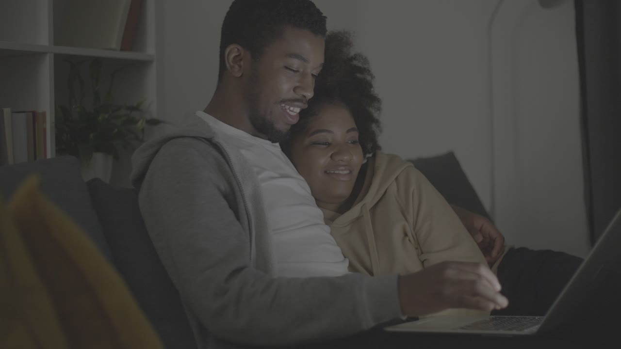 jovem casal afro-americano escolhendo um filme para assistir no laptop