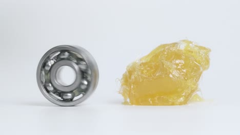 kugellager drehen neben gelbes lithiumfett (nlgi 2) und bewegen sich zu fett isoliert auf weißem hintergrund. verschleiß- und rostschutz. reduzieren sie reibung. ingenieur- und industriekonzept