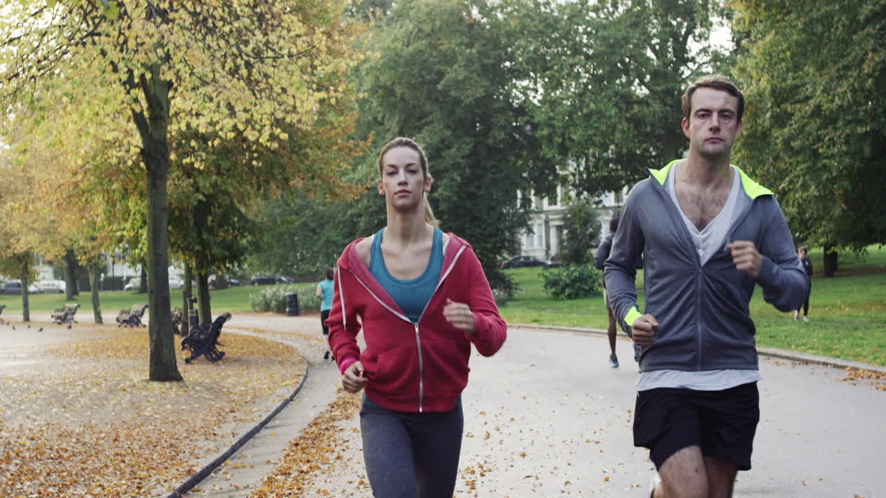 Athletic couple running in park wearing wearable technology connected devices