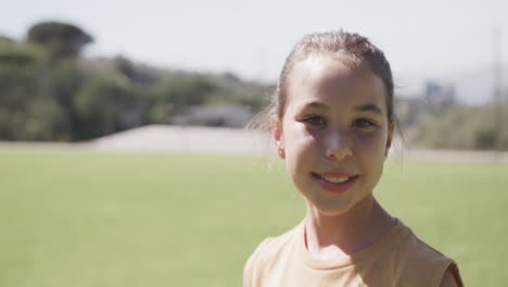 portrait of happy biracial girl on sunny elementary school playing field, copy space, slow motion