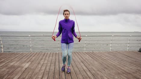 young athletic woman working out on the jump rope. slim girl jumping on a skipping rope by the sea. slow motion shot