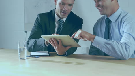 Animation-of-statistical-data-processing-over-diverse-businessmen-discussing-over-tablet-at-office