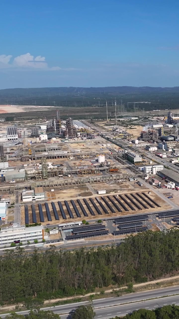 An oil refinery complex and petroleum production facility is showcased from above, highlighting the industrial processing systems and energy infrastructure in operation during daylight hours.