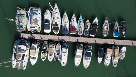 harbor with moored sailing boats to the pier at latchi port, aerial rise up view