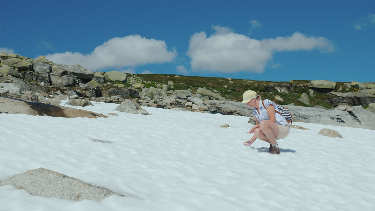 한 여성이 여름날 눈의 잔해에서 즐거운 시간을 보내고 있습니다. 노르웨이의 놀라운 자연
