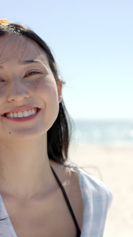vertical video: smiling woman enjoying sunny day at beach, relaxing and having fun