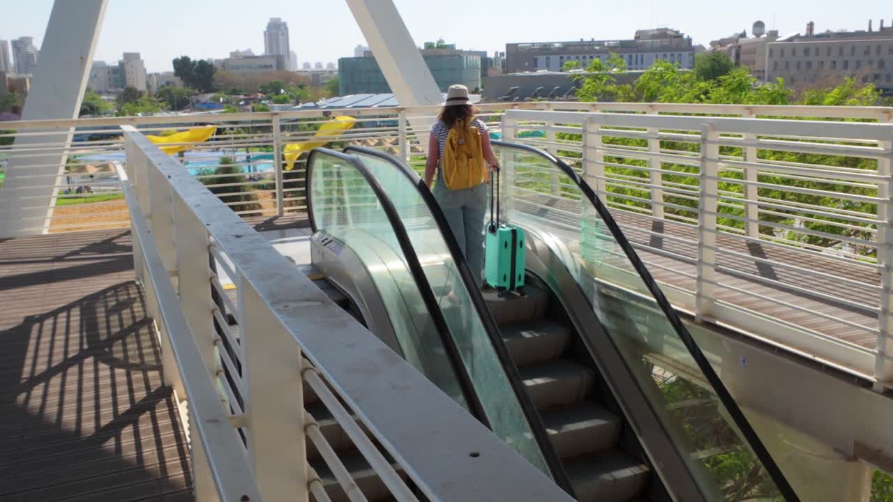 A woman is walking up an escalator with a suitcase
