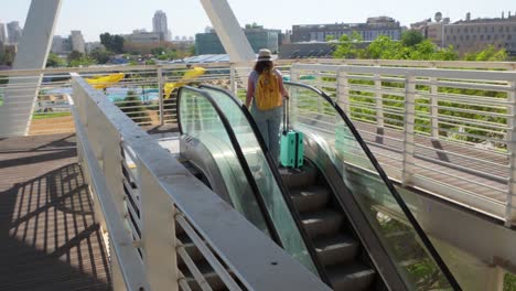 a woman is walking up an escalator with a suitcase