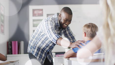 animation of light spots over happy african american male teacher congratulating schoolboy at desk