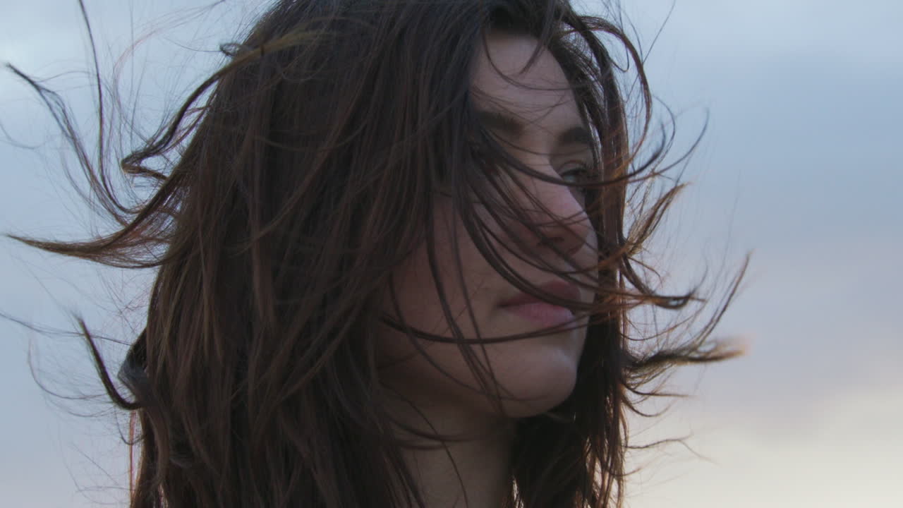 chica caucásica parada afuera durante el clima ventoso