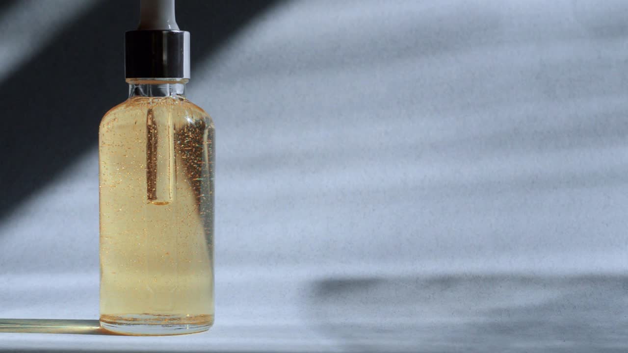 유리 병의 기름은 빛 표면에 어져 있으며 공기 거품이있는 화장품 기름입니다.