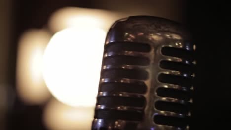 a close-up encounter with a vintage microphone illuminated by a warm glow, capturing the essence of music and performance atmosphere in an intimate setting