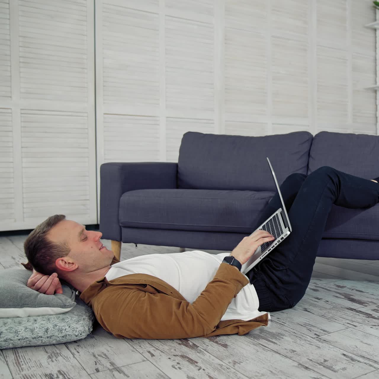 Man using laptop at home. Handsome man using laptop while lying on the floor