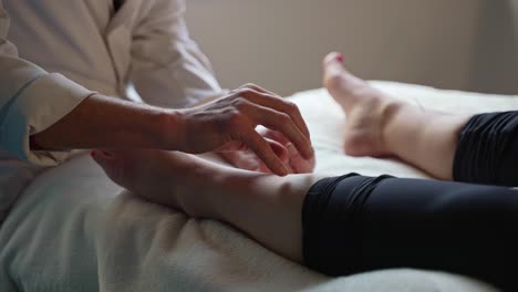 holistic therapist adjusting acupuncture needle on female patients left leg