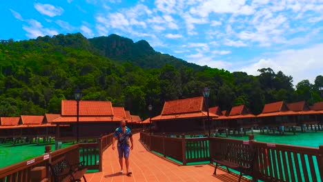 a relaxed man on a stilt of a luxury hotel looks out to sea in langkawi island
