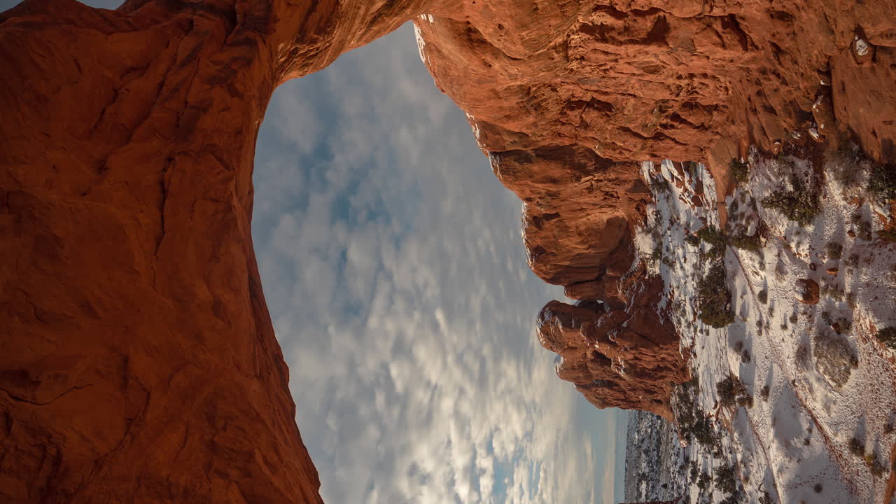 Time lapse 4K vertikal, awan bergerak di atas lengkungan batu pasir merah alami yang menakjubkan di Taman Nasional Arches, Utah AS