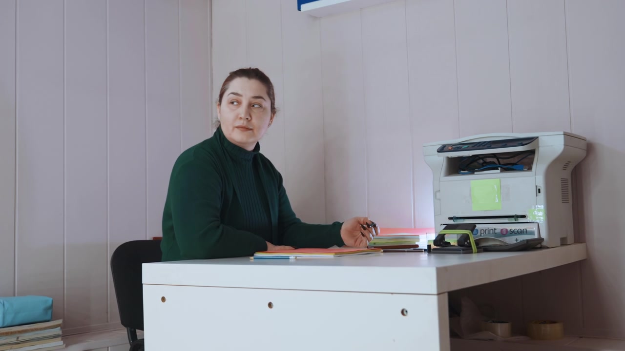 Sykepleier organiserer filer. Fokusert klinisk sykepleier sorterer og arkiverer pasientdokumentasjon omhyggelig. Rolig og oppmerksom sykepleier organiserer pasientfiler nær arbeidsstasjon og utskriftsenhet effektivt