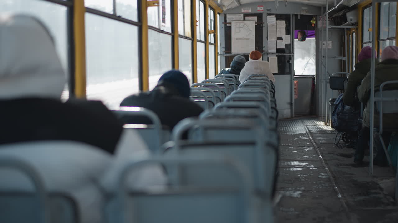 side view of busy city street with yellow minibus driving past pedestrians and market stalls, surrounded by urban buildings and tangled overhead cables under bright daylight