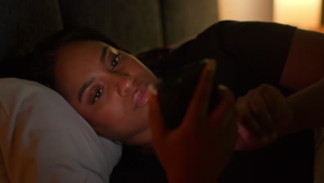 woman using phone in bed at night