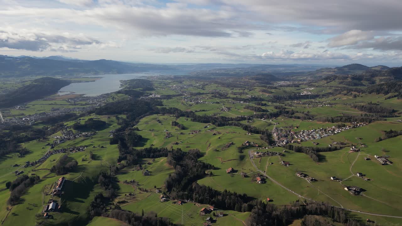 Ripresa panoramica con drone all'indietro di una vivace campagna montuosa, auto che percorrono la strada