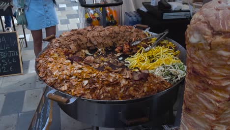 large pan of döner kebab meat and french fries at a street food stall