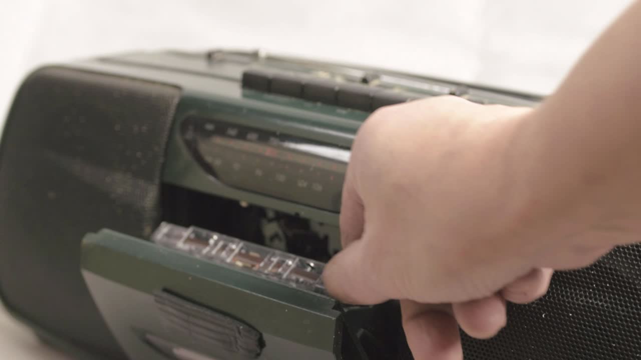 Hand ejecting retro cassette tapes from radio cassette player medium shot