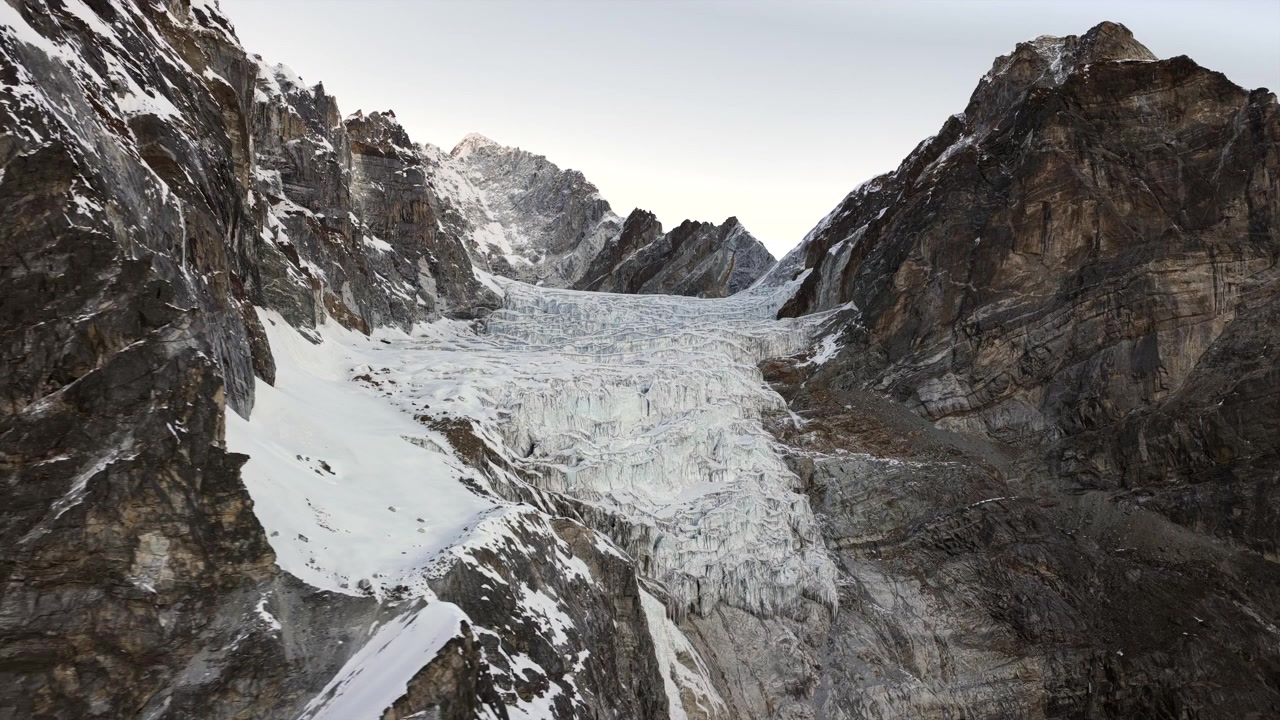 Tomada ampla de drone movendo-se para a direita enquanto faz panorâmica para a esquerda para revelar lentamente uma geleira maciça, fendas profundas e formações de gelo acidentadas na região do Everest, no Nepal