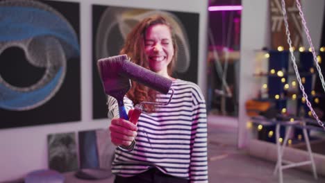 a smiling painter is standing with tools and looking at the camera