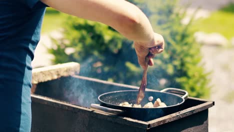 close-up slow motion man cooks pilaf in cauldron on coals on a grill stir the meat