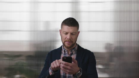 Retrato-De-Un-Hombre-De-Negocios-Profesional-Enviando-Mensajes-De-Texto-Navegando-Usando-Tecnología-De-Redes-Móviles-De-Teléfonos-Inteligentes-Revisando-Mensajes-En-El-Fondo-Del-Espacio-De-Trabajo-De-Oficina-Ocupado