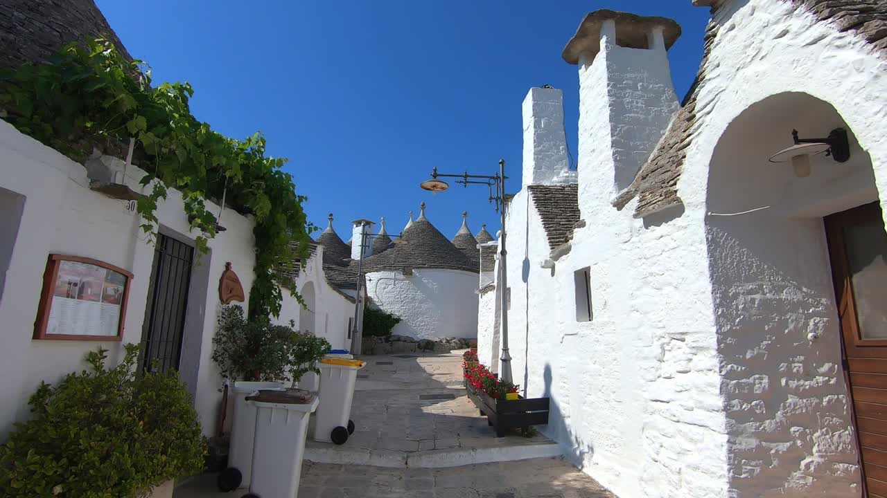 caminando por la calle del sitio patrimonial de alberobello en un día soleado