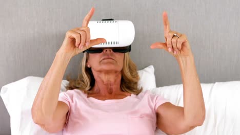 Senior-woman-using-virtual-reality-headset-on-bed-in-bedroom