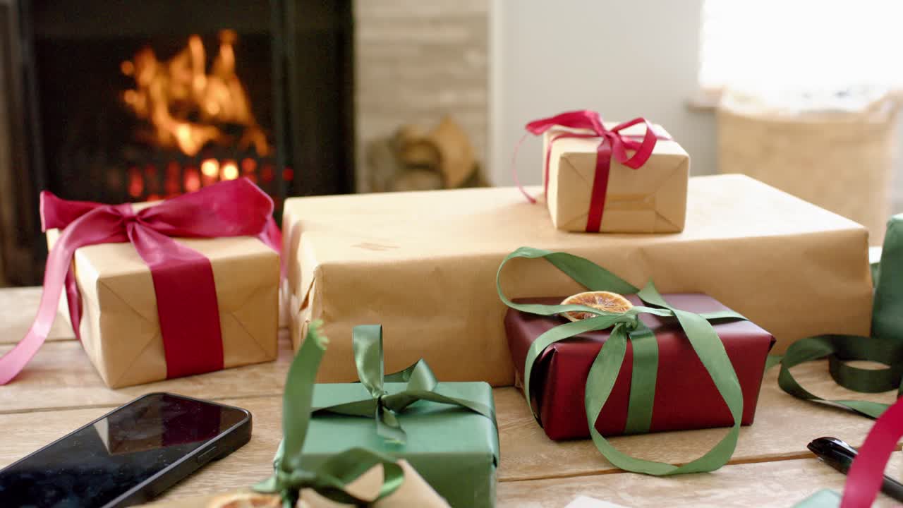 Camino con ceppi accesi, che proietta fiamme tremolanti su scatole regalo incartate sul tavolo, riscaldando la stanza