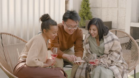 an young man showing something funny on his phone to two young beautiful girls