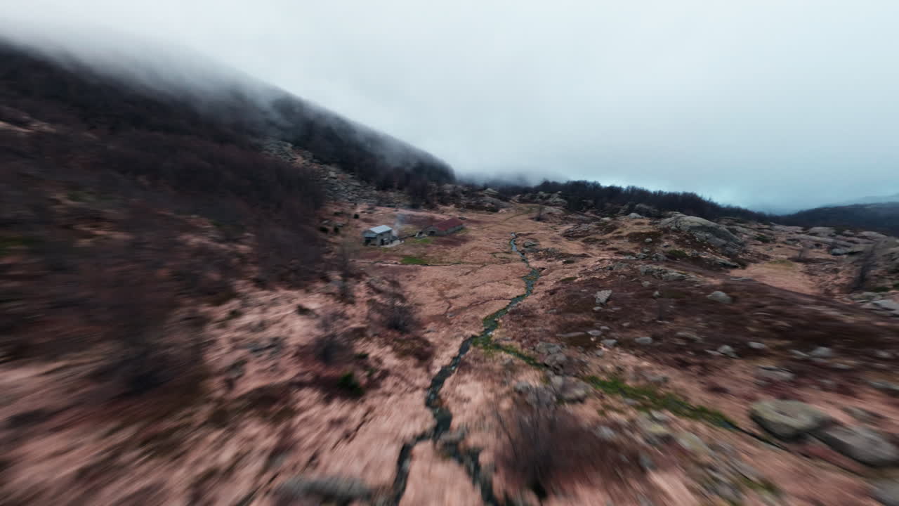 Foggy mountain valley shot by FPV drone, rugged terrain and wild solitude mood
