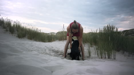 slow motion of a young woman playing with her dog on the beach