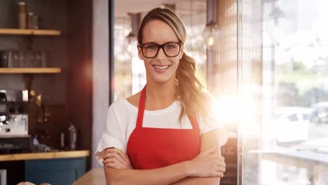 Portrait-of-smiling-waitress-standing-with-arms-crossed